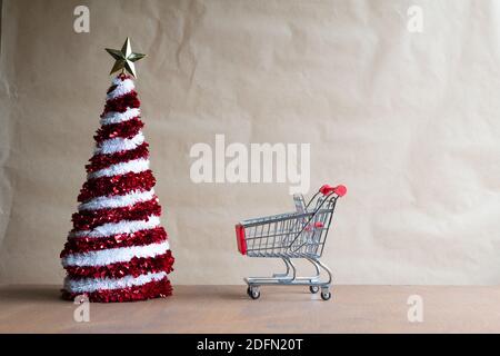 Albero di Natale in miniatura in un carrello dal negozio e una sveglia su una finestra invernale, il concetto di vendite di Natale Foto Stock