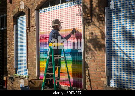 Un uomo crea un motivo colorato mentre si sale su il suo Affari nel centro di Minneapolis durante le rivolte di George Floyd Foto Stock