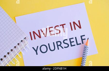 Cartello con scritto Invest in yourself. La foto concettuale migliora le tue competenze prendere corsi Do maestri Borse, matita, white paper con testo INVESTIRE i Foto Stock