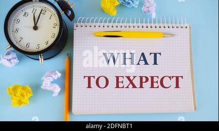 Scrittura a mano di testo che cosa aspettarsi. Concetto che significa chiedere circa considerare qualcosa come probabile accadere. Carta stropicciata, sveglia e penci Foto Stock