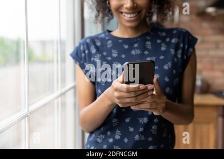 Primo piano felice multirazziale giovane donna utilizzando il telefono cellulare. Foto Stock