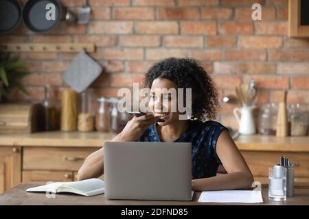 Sorridente giovane razza mista donna dettando messaggio audio. Foto Stock