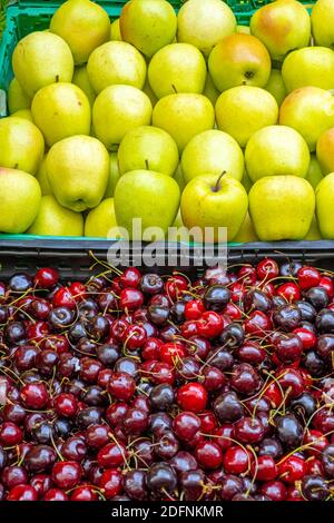 Ciliegie e mele in vendita in un mercato Foto Stock