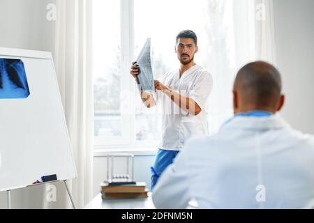 Due medici di sesso maschile esaminano la risonanza magnetica cerebrale di un paziente nel cabinet Foto Stock