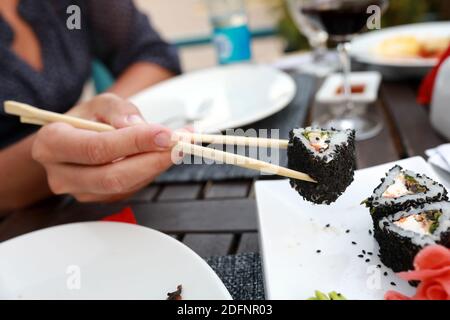 La persona prende il sushi al tavolo nel ristorante Foto Stock