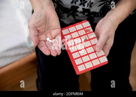 Le donne più anziane che prendono i farmaci al tavolo, donna anziana che prepara le pillole, preparano la compressa quotidiana della medicina in pillbox Foto Stock