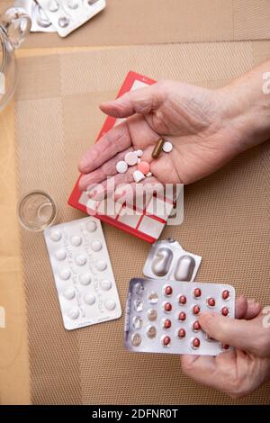 Le donne più anziane che prendono i farmaci al tavolo, donna anziana che prepara le pillole, preparano la compressa quotidiana della medicina in pillbox Foto Stock