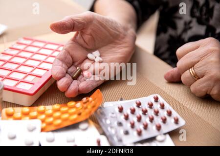 Le donne più anziane che prendono i farmaci al tavolo, donna anziana che prepara le pillole, preparano la compressa quotidiana della medicina in pillbox Foto Stock