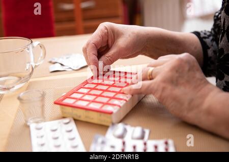 Le donne più anziane che prendono i farmaci al tavolo, donna anziana che prepara le pillole, preparano la compressa quotidiana della medicina in pillbox Foto Stock