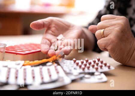 Smistamento pillole, mani anziane smistamento pillole, pillole in mani di un anziano. Vecchiaia dolorosa. Cura della salute degli anziani Foto Stock