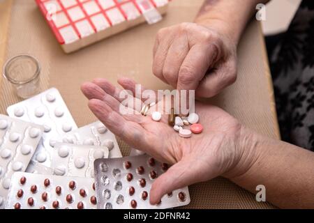 Le donne più anziane che prendono i farmaci al tavolo, donna anziana che prepara le pillole, preparano la compressa quotidiana della medicina in pillbox Foto Stock