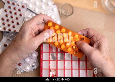 Le donne più anziane che prendono i farmaci al tavolo, donna anziana che prepara le pillole, preparano la compressa quotidiana della medicina in pillbox Foto Stock