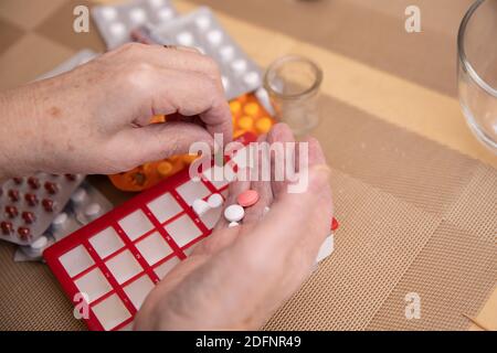 Le donne più anziane che prendono i farmaci al tavolo, donna anziana che prepara le pillole, preparano la compressa quotidiana della medicina in pillbox Foto Stock