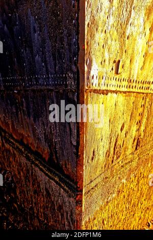 Arrugginite piastre in acciaio su un vecchio scafo di navi al tramonto Foto Stock