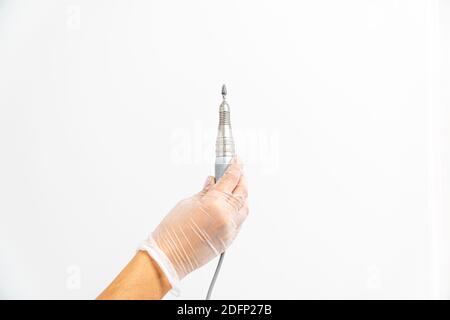 Primo piano della mano di un podiatrist guanto che tiene una lucidatrice su sfondo bianco Foto Stock