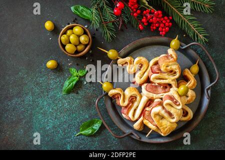 Spuntino di Natale albero di Natale con olive e pancetta e decorazioni natalizie su un tavolo di ardesia. Natale e Capodanno sfondo per il cibo. Vista dall'alto piatta Foto Stock