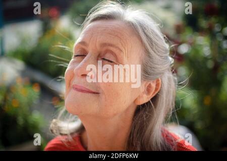 Ritratto bianco e nero di donna anziana con capelli grigi e faccia con le rughe all'aperto rilassandosi al parco Foto Stock