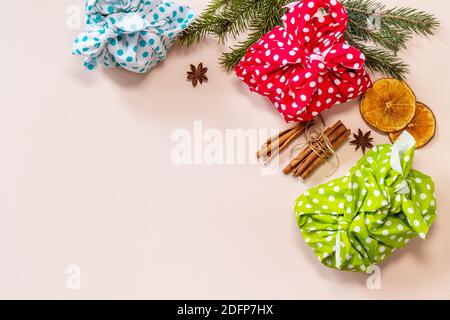 Regali di Natale furoshiki su sfondo rosa. Concetto di vacanza di natale eco. Vista dall'alto in posizione piatta. Spazio di copia. Foto Stock
