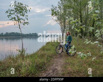 Józefów, Polonia - 29 aprile 2019: Una donna in bicicletta sul sentiero lungo il fiume Vistola. Riserva dell'isola di Świderskie. Distretto Masoviano. Polonia, Europa. Foto Stock