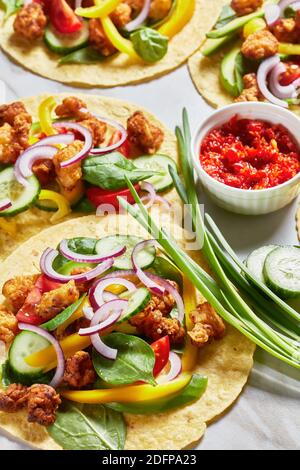 tacos di pollo con avocado, cetriolo, foglie di spinaci freschi, strisce di pepe e cipolla su un tavolo di marmo, cucina messicana, vista verticale da abov Foto Stock