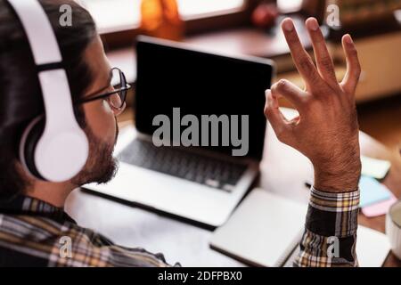 Gli studenti che gesturano bene a schermo vuoto imparare online in interni, vista posteriore Foto Stock