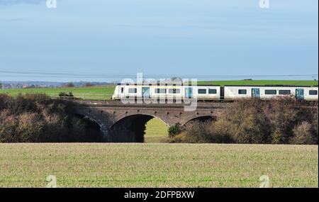 Classe 700 EMU treno suburbano che attraversa il ponte stradale in campagna tra Hitchin e Letchworth, Hertfordshire, Inghilterra, Regno Unito Foto Stock