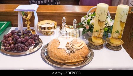 Simboli eucaristici: Pane, vino, calice, uva, candele pasquali e ostia durante la celebrazione della prima comunione Santa Foto Stock