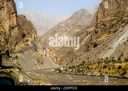 Il fiume Panj si snoda attraverso una stretta gola rocciosa nel distretto di Darvoz, in Tagikistan, una strada stretta corre lungo il pendio ripido. Foto Stock
