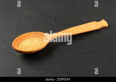 Grande cucchiaio di legno con zucchero di canna su fondo di cemento Foto Stock