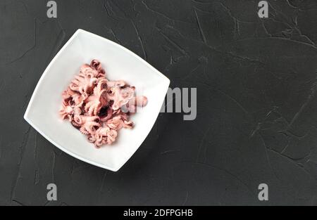 Piccoli polpi in un piatto bianco su sfondo scuro vista dall'alto Foto Stock