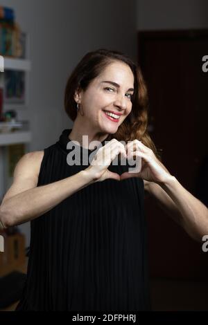 Felice donna di mezza età con un sorriso toothy che fa la forma di un cuore con le sue mani. Foto Stock