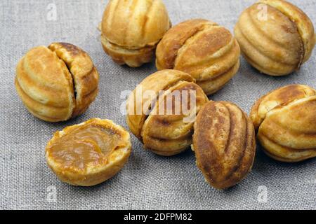 Biscotti fatti in casa, noci con latte condensato. Frollette fatte in casa. Deliziosi biscotti. Biscotti fatti in casa farciti con latte condensato bollito su un grigio Foto Stock