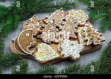 Composizione di Capodanno con pan di zenzero e rami di abete. Biscotti di pan di zenzero ricoperti di smalto bianco di diverse forme su una tavola di legno. Natale Foto Stock