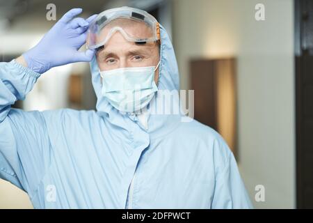 Impiegato di sesso maschile che esegue la disinfezione in indumenti protettivi speciali e indossare occhiali. Concetto di coronavirus e quarantena Foto Stock