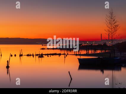 Tramonto sul lago, molo in legno e vecchia barca da pesca Foto Stock