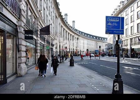 Regent Street, una famosa via dello shopping a Londra, Regno Unito. Gli autobus rossi passano su e giù per la strada e i pedoni camminano lungo trasportare borse di shopping. Foto Stock