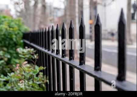 Primo piano di una ringhiera nera in un parco con Sfondo sfocato di una via di Londra Foto Stock