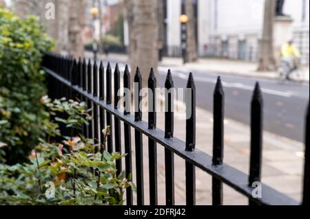 Primo piano di una ringhiera nera in un parco con Sfondo sfocato di una via di Londra Foto Stock