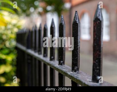 Primo piano di una ringhiera nera in un parco con Sfondo sfocato di una via di Londra Foto Stock