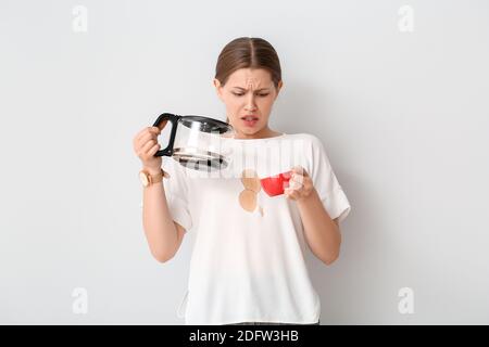 Giovane donna stressata con macchie di caffè sulla sua t-shirt sfondo bianco Foto Stock