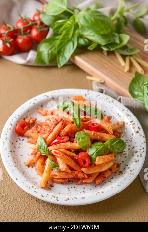 Piatto di deliziosa pasta di penne con salsa di pomodoro a colori sfondo Foto Stock