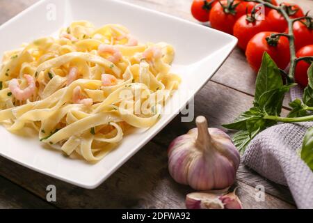 Piatto di pasta gustosa con gamberi su tavola di legno Foto Stock