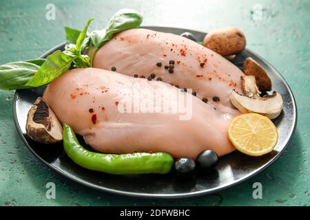 Piatto con filetto di pollo crudo su sfondo scuro Foto Stock