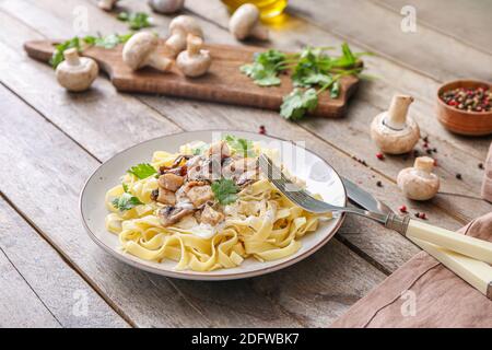 Piatto di gustosa pasta con pollo e funghi su legno tabella Foto Stock