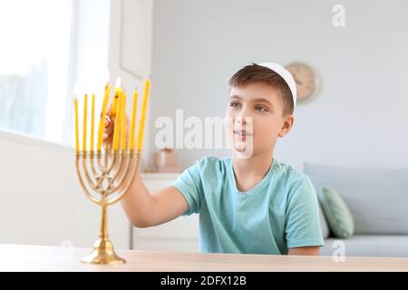 Happy boy che illumina le candele per celebrare Hannukah a casa Foto Stock