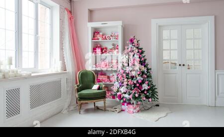 Bellissima vacanza decorate con alberi di Natale, mensola e rosa doni blu su di esso, sedia verde home interno Foto Stock
