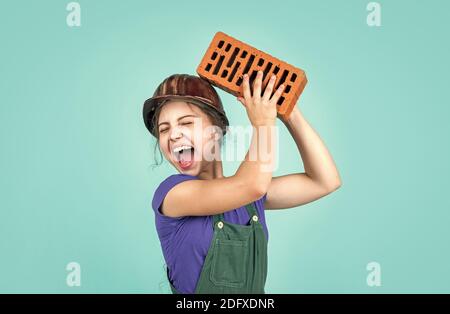 oh no. Piccola ragazza muratore. Imparando come costruire. Piccolo lavoratore nella costruzione del casco da mattone. Architettura costruzione bambino. Bambino in uniforme lavorando intorno muro di mattoni. Concetto di giorno di lavoro. Foto Stock