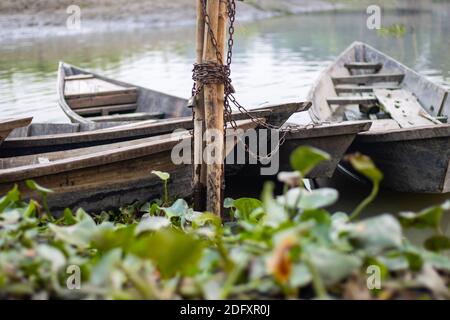 Parcheggiate piccole barche in legno con catena di ferro accanto al fiume Foto Stock