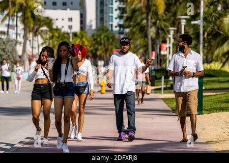 Fotografia di strada giovani turisti a Miami Beach camminando sull'oceano Guida Foto Stock