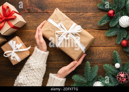 Regali di Natale su sfondo di legno in mani femminili. Vista dall'alto Foto Stock